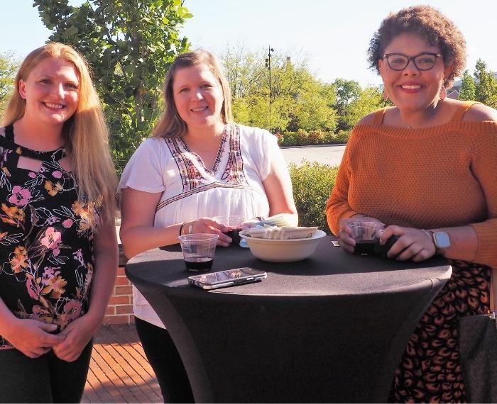 Three woman standing at table smiling