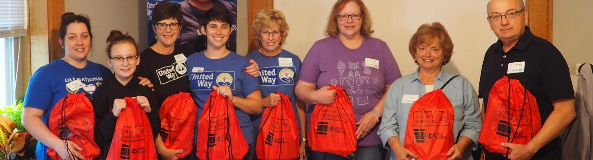 People smiling and holding backpacks