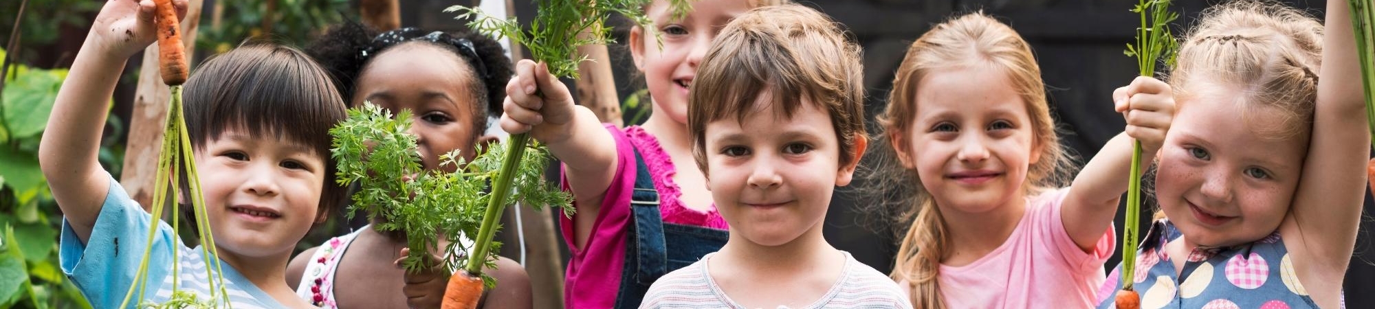 Group of children holding up garden vegetables