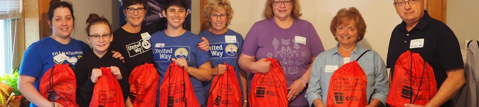 People smiling and holding backpacks