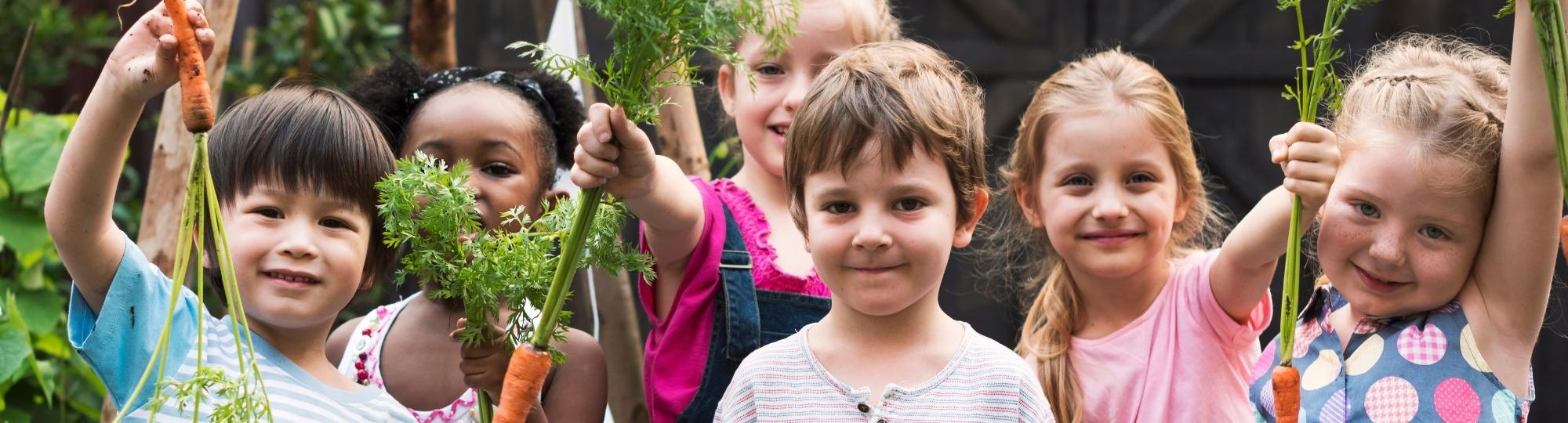 Group of children holding up garden vegetables
